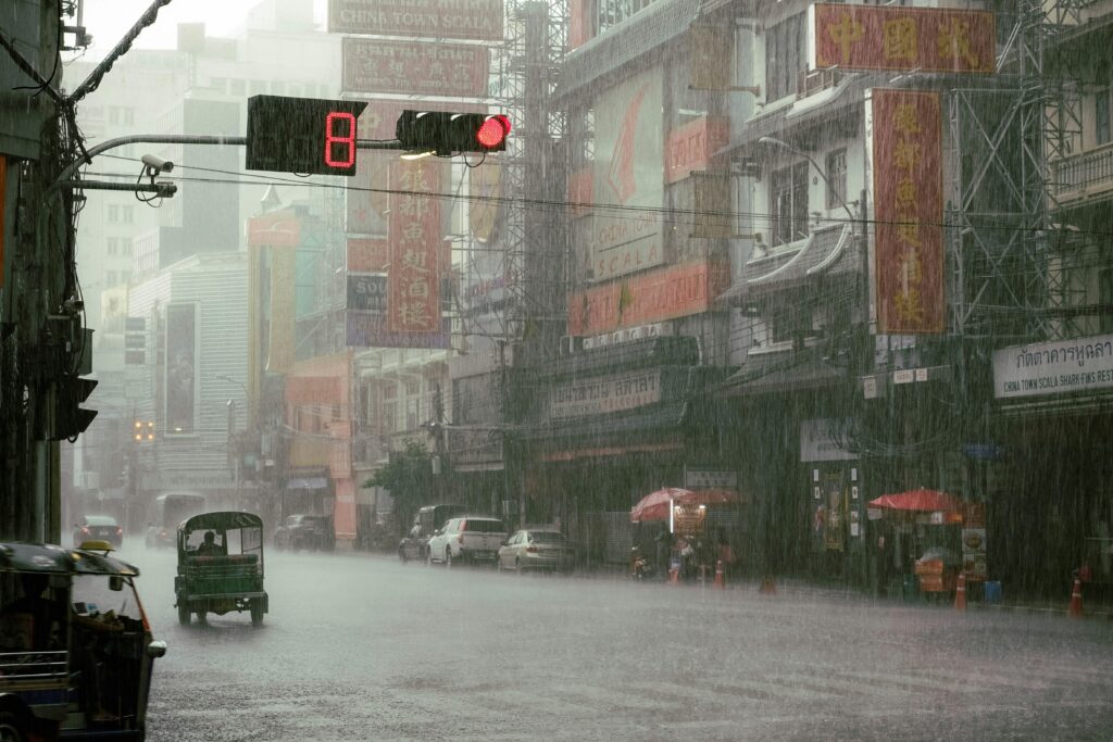 A traffic light on road with cars under the rain